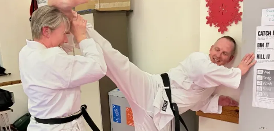 Adult members of Maesteg Shotokan Karate Club practising a high kick during training
