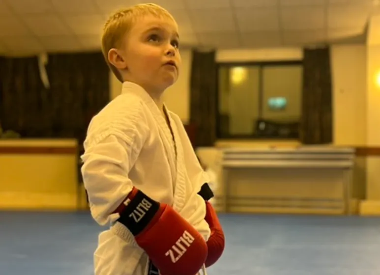 Young Maesteg Shotokan Karate Club member in karate gi and red sparring gloves at Bryn Community Hall